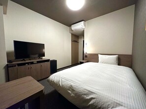 A hotel room with a bed, a TV on a wooden cabinet, a desk, and an air conditioning unit on the wall. - Hotel Route Inn Numata (Numata)