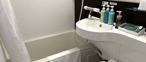 Un baño con un lavamanos blanco, una ducha de mano, un inodoro y una toalla colgada en la pared.