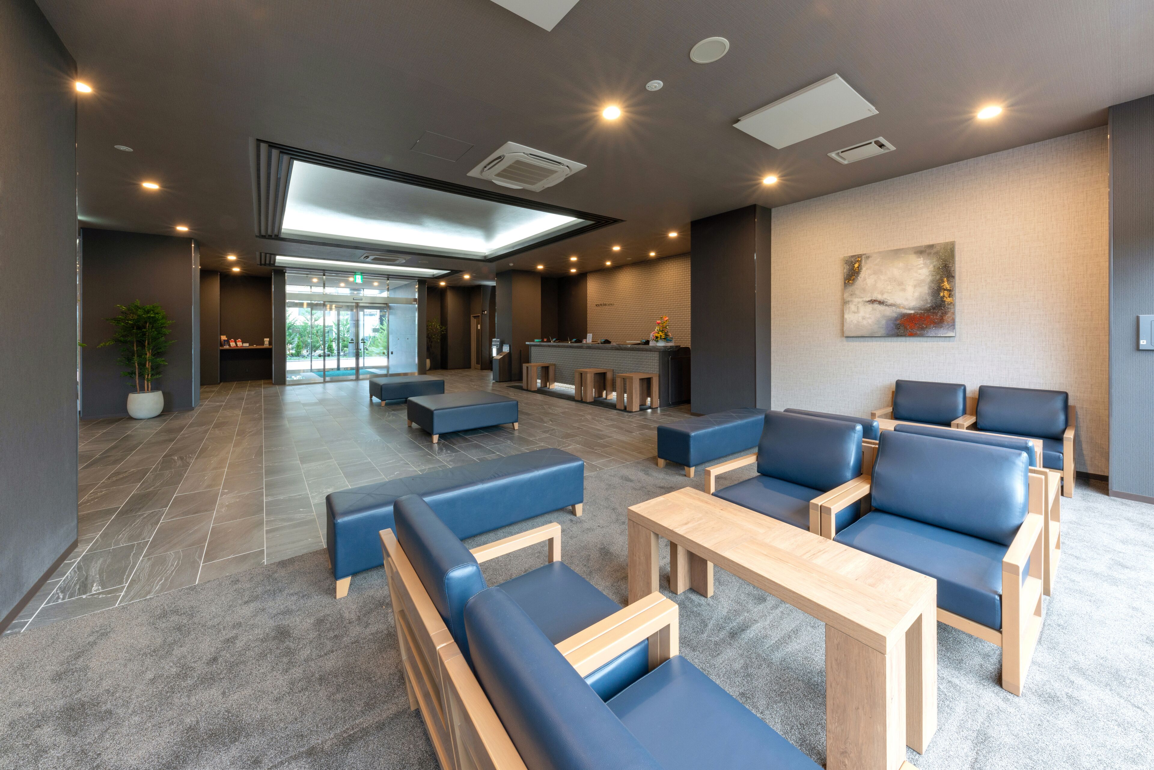 A modern lobby with seating areas, a reception desk, and a large window.