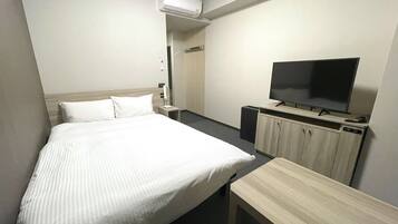 Quarto de hotel com cama, televisão, escrivaninha e guarda-roupa.