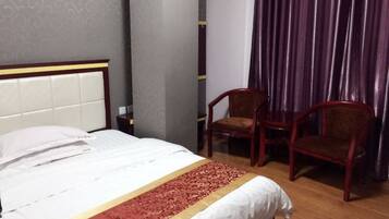 A hotel room with a bed, two wooden chairs, a red carpet, and a curtain.