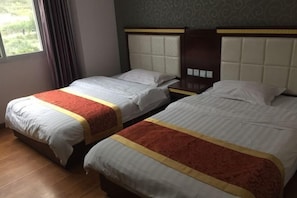 Dos llits individuals amb els capçals, una finestra amb cortines i una paret amb dibuixos.