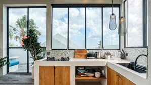 A modern kitchen with a large window, a built-in stove, and a sink. - Zig Zag Loft (Canggu)