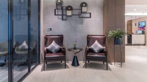 Un área de recepción moderna con dos sillones de cuero, una mesita redonda y un elemento decorativo en la pared.