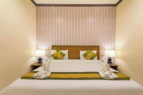 Une chambre d’hôtel avec un lit, deux tables de chevet, des lampes et des serviettes disposées sur le lit.
