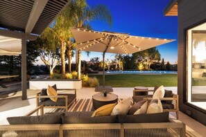 Un espacio al aire libre con patio, sofá, mesas redondas y sombrillas.