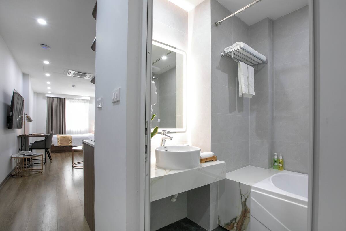 A modern hotel bathroom with a large sink, a bathtub, and a shower area.