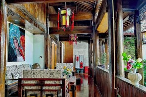 A traditional wooden interior with a sofa, a dining table, and a large painting on the wall. - Nalan Ge homestay (Lijiang)