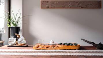 Een houten tafel met een plant in pot, glazen potten, een theepot en een dienblad met groene thee.