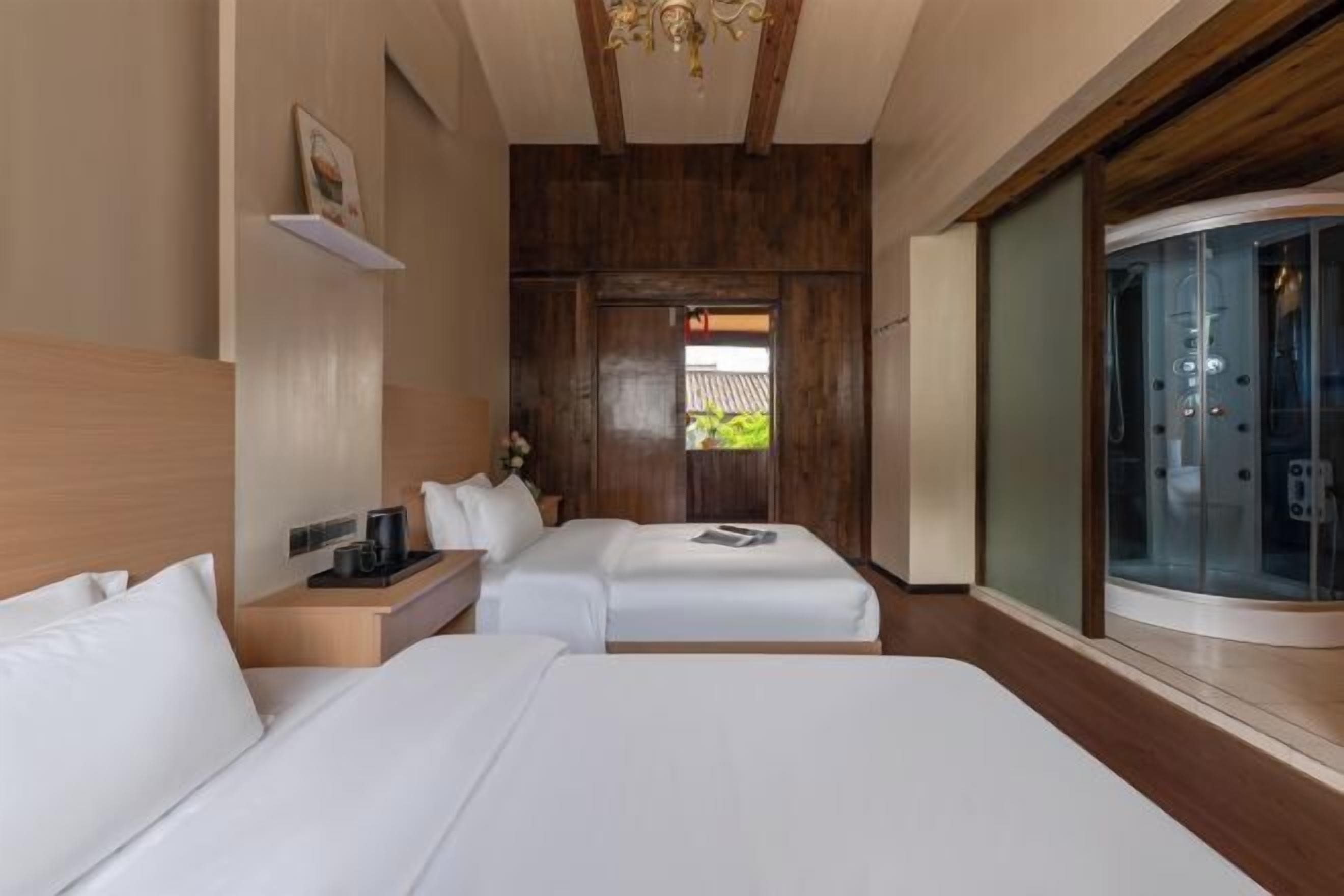 Quarto de hotel com duas camas, teto de madeira, box de vidro no chuveiro e vista para o verde lá fora.