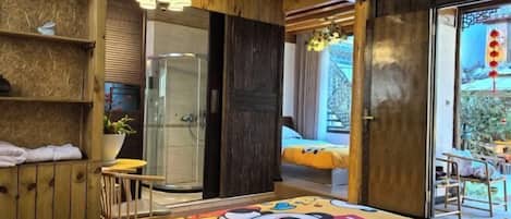 A room with a bed, wooden walls, a small table, and a window with a view.