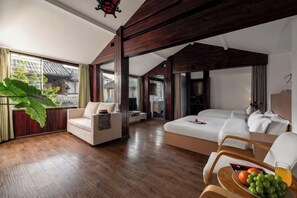 A spacious room with a large bed, a sofa, and a dining table with fruits and a drink. - Nalan Ge homestay (Lijiang)