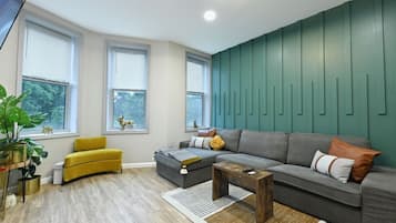 Een moderne woonkamer met een grijze bank, een gele fauteuil en een houten salontafel.