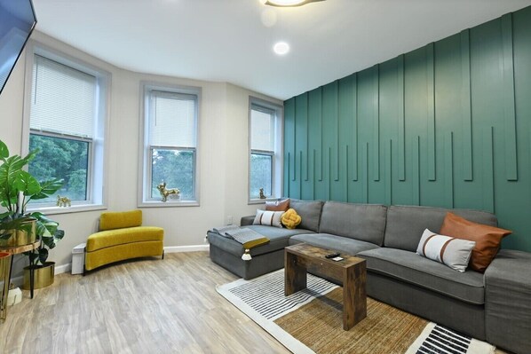 A modern living room with a grey sofa, yellow armchair, and a wooden coffee table.