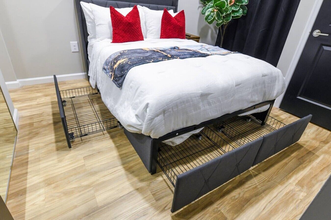Een bed met hoofdbord, wit beddengoed en rode kussens.