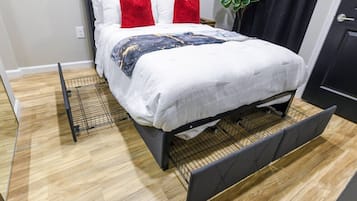 Een bed met hoofdbord, wit beddengoed en rode kussens.