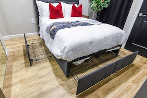 A bed with a headboard, white bedding, and red pillows.
