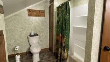 Un bagno con il water, una tenda per la doccia e un cartello a parete.