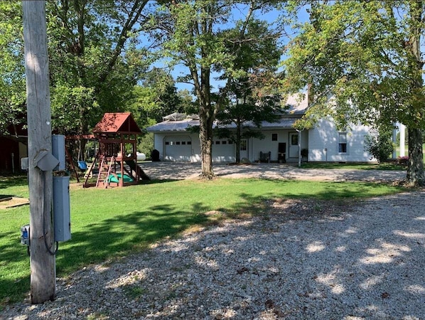 A house with a front yard, a swing set, and a gravel driveway. - Peaceful Meadows - Peaceful Meadows (Flat Rock)