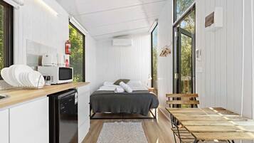 A compact room with a bed, a small kitchenette, and a dining area.