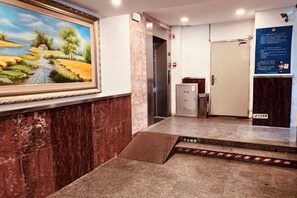 A hotel lobby with a marble floor, a reception desk, a painting, and an elevator. - Guangdong Educational Activities Center (Guangzhou)