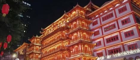 Un bâtiment traditionnel à plusieurs étages, doté d’une architecture richement décorée et de fenêtres illuminées.