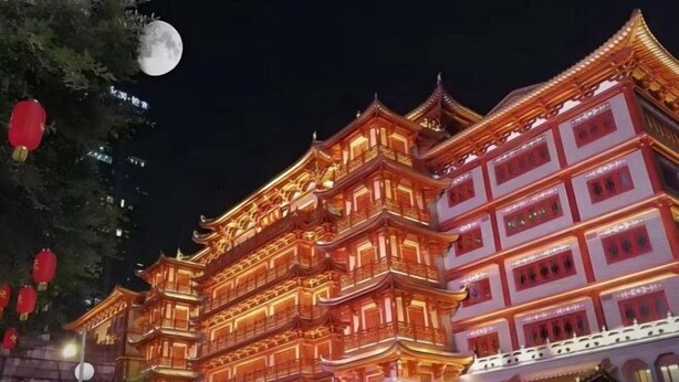 A traditional multi-story building with ornate architecture, illuminated at night.