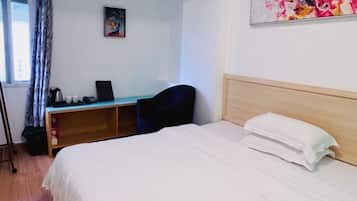 A hotel room with a bed, a desk, and a chair.
