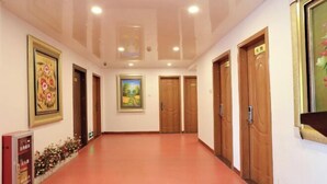 A hallway with wooden doors, a framed painting, and a poster on the wall.