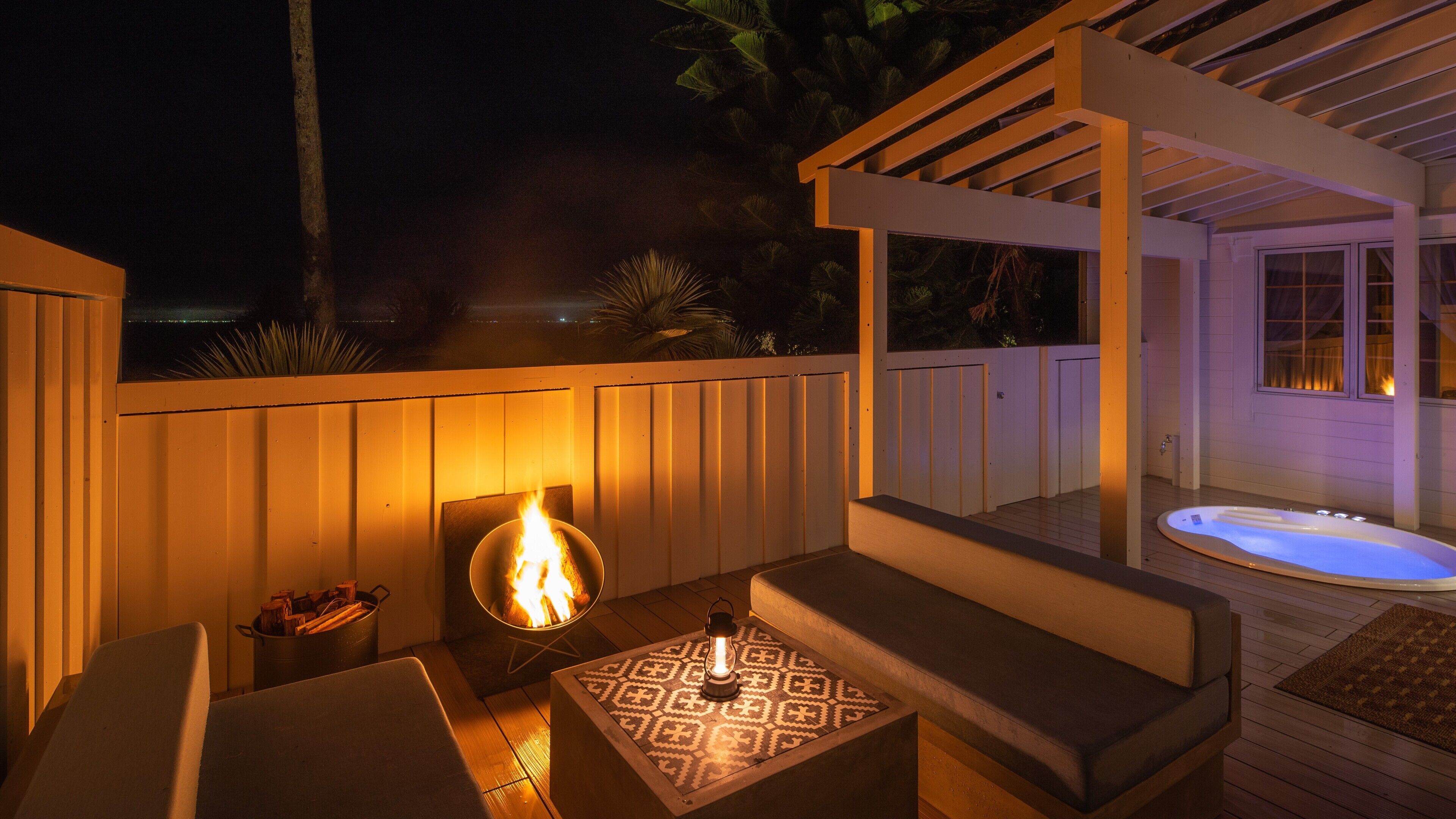 Un patio al aire libre con una chimenea, asientos y un jacuzzi.