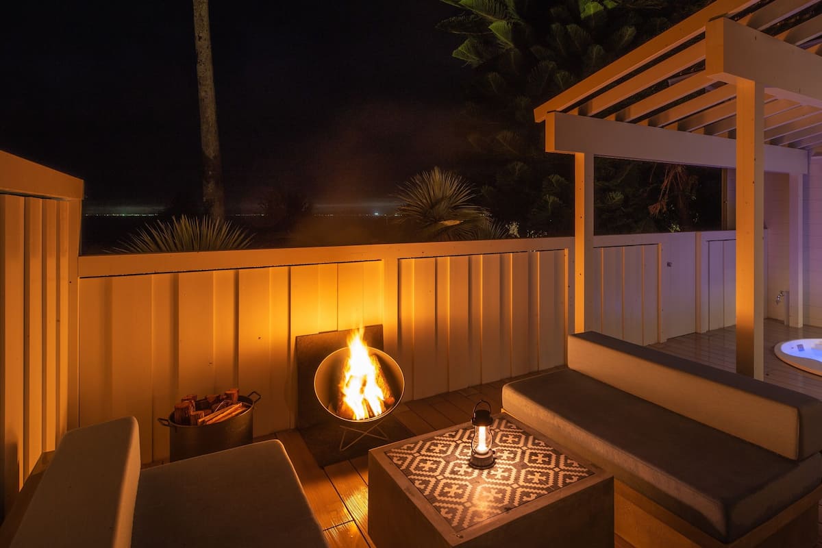 Un patio al aire libre con una chimenea, asientos y un jacuzzi.