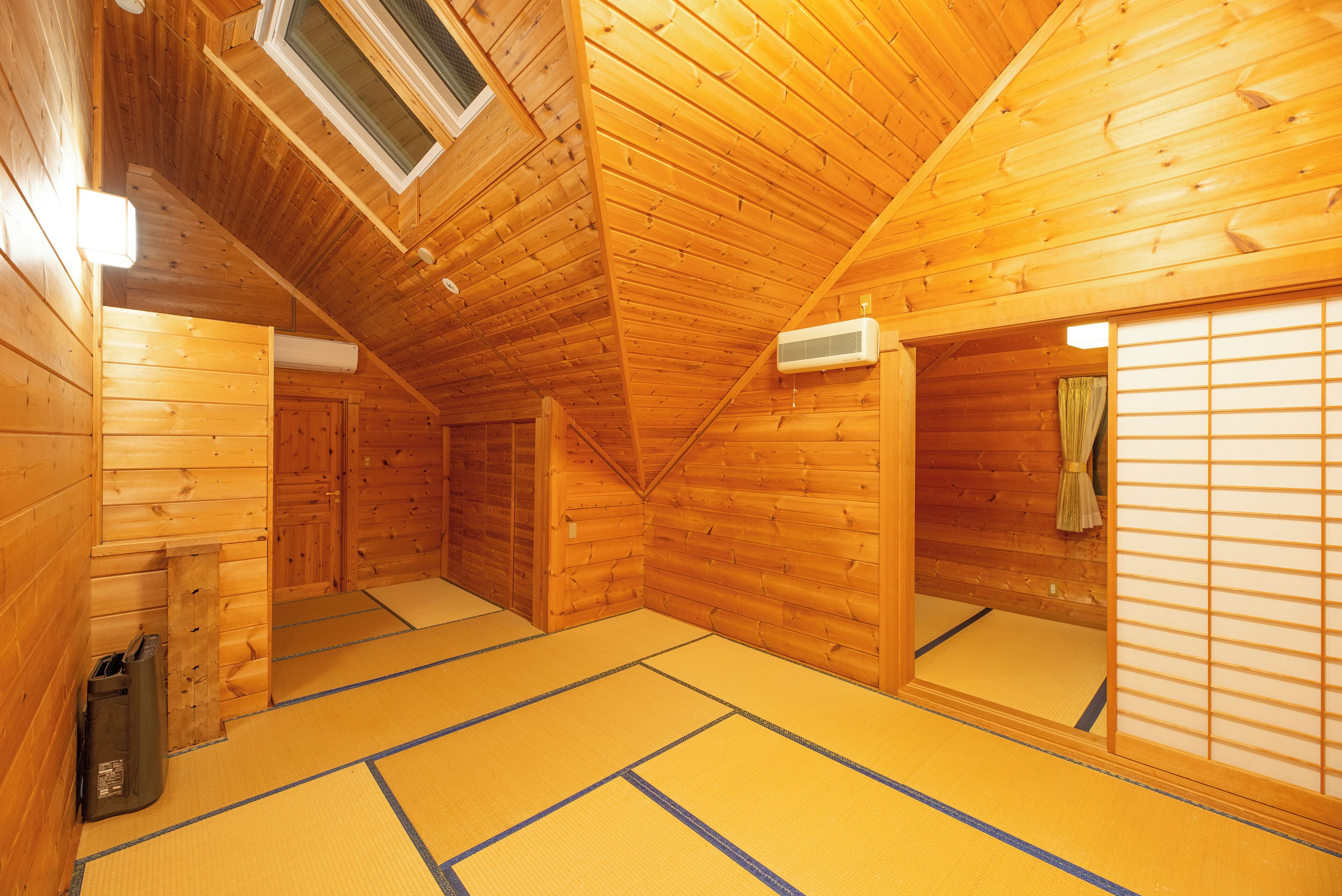 A traditional wooden room with tatami flooring, a sliding door, and a ceiling vent.
