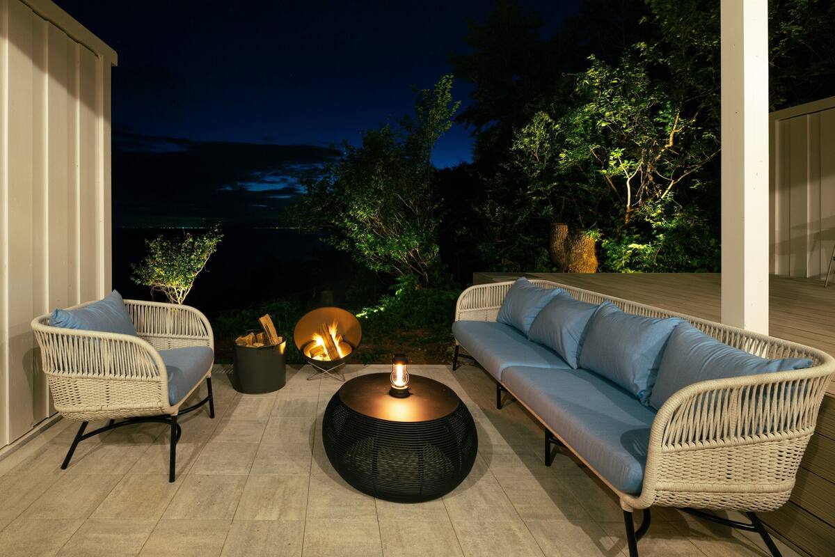 An outdoor patio with wicker furniture, a fire pit, and a lantern.