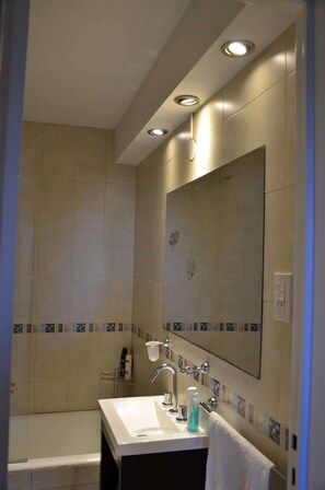 Bathroom features a large mirror, sink, and bathtub.