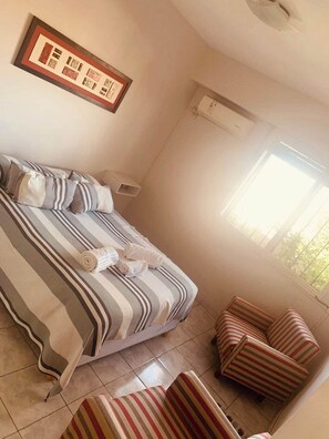Relax in a comfortable room with a neatly made bed, a framed picture, and a cozy seating area.