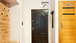 A hallway with a wooden floor, a black door with a glass panel, and a wooden WC door. - Warszauera 11/1 (Kraków)