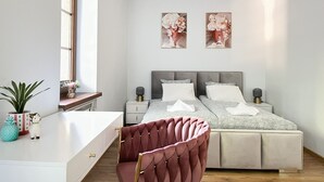 A bedroom with a bed, bedside tables, a desk, a chair, and two wall-mounted paintings. - Warszauera 11/1 (Kraków)