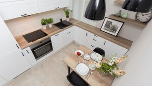 A modern kitchen with white cabinets, a wooden countertop, and a dining area with a table set for two.