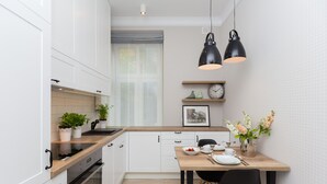 A modern kitchen with white cabinets, a wooden countertop, and a dining area with a table and chairs.