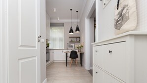 A modern kitchen with white cabinetry, a dining area with a black chair, and pendant lights.