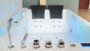 Une salle de bain moderne équipée d’une baignoire, d’une douchette et d’un panneau de commande.