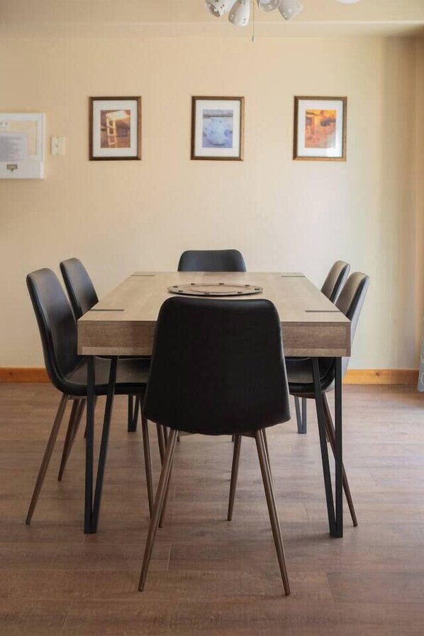A dining area with a rectangular table, six black chairs, and three framed pictures on the wall. - Moab Rim Views, Pool, Decks, Steps to Hiking & Trails – Sleeps 6 (Moab)