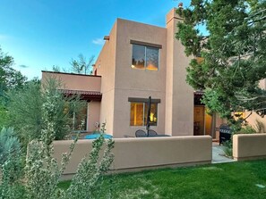 A modern two-story house with a flat roof, a patio with outdoor furniture, and a barbecue grill. - Moab Rim Views, Pool, Decks, Steps to Hiking & Trails – Sleeps 6 (Moab)