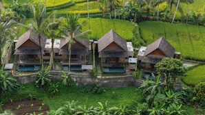 Un complexe hôtelier comprenant plusieurs bâtiments de style bungalow, chacun doté d’une piscine et entouré d’une végétation luxuriante et de rizières.