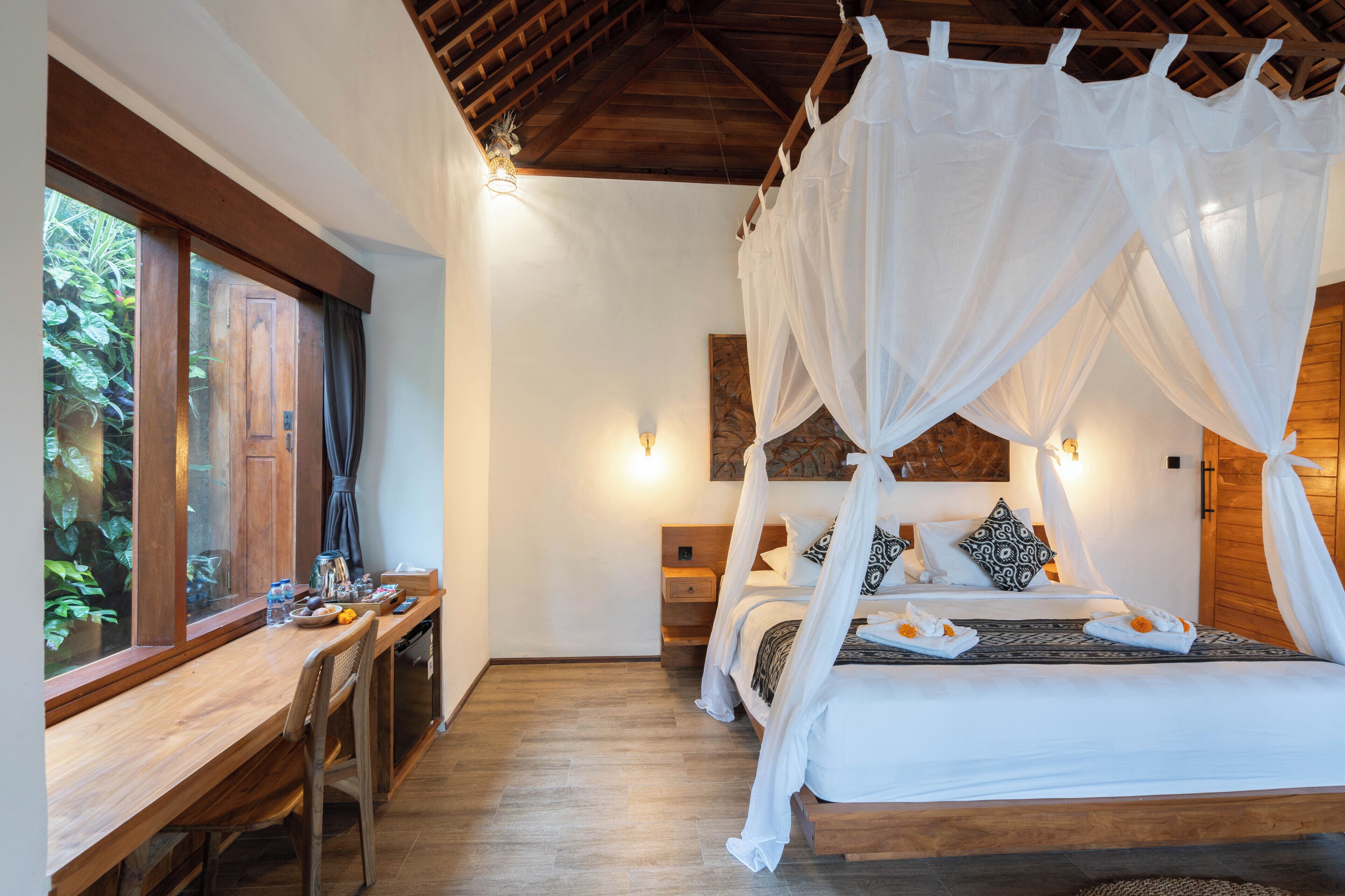 A bedroom with a wooden bed, white canopy, bedside tables, and a window with curtains.