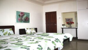 A bedroom with a bed, a wooden door, a white wardrobe, and a small table with a vase of flowers. - Rm 101 at Liezels B&B in Palompon, / Kalanggaman Island. (Palompon)