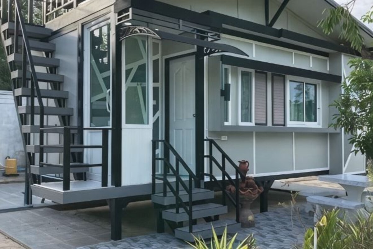 A modern building with a staircase leading to a covered area, a door, and a bench.