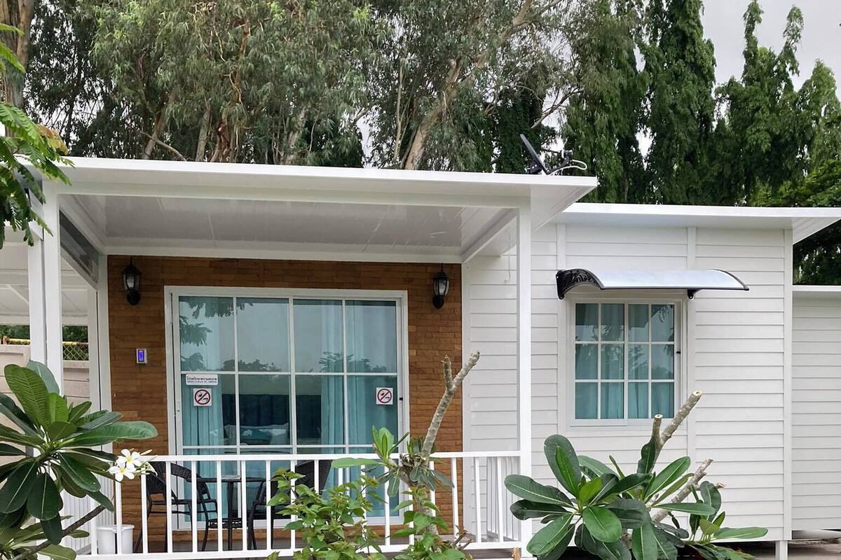 A modern house with a covered porch, a sliding glass door, and a small garden area with plants.