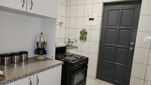 Una cocina con armarios blancos, una estufa negra y una puerta negra.