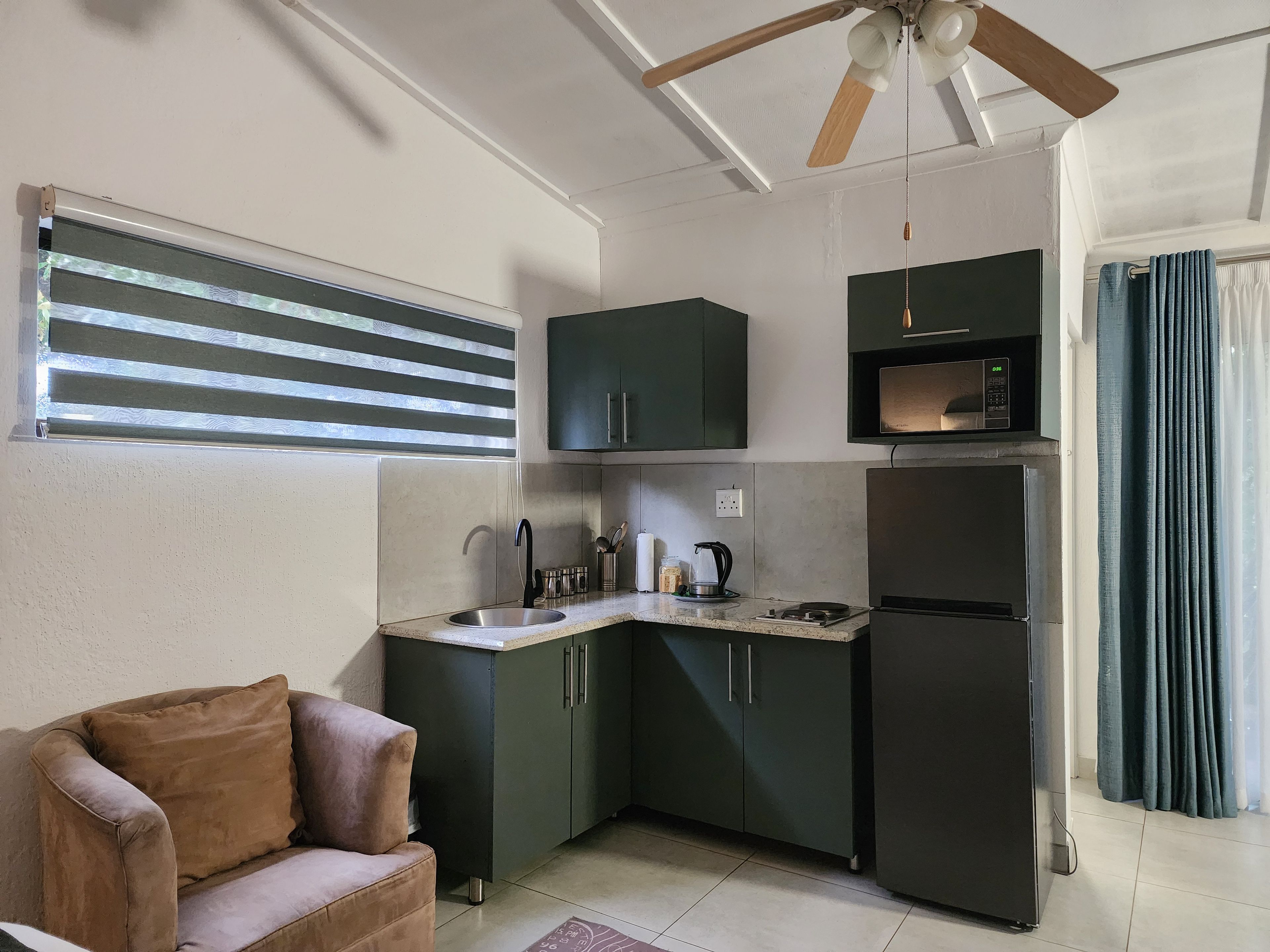 A compact kitchen with dark cabinets, a built-in microwave, and a ceiling fan.